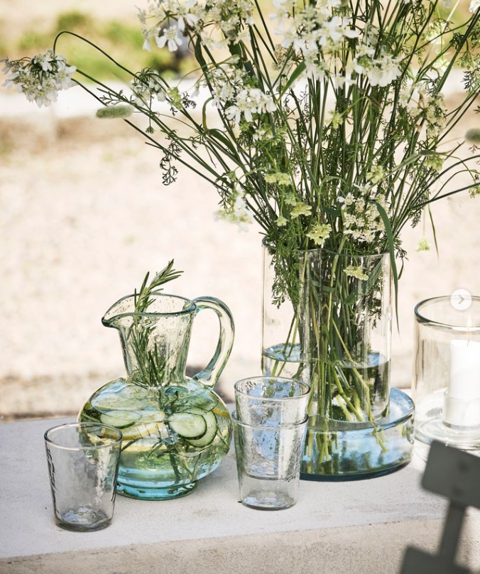 Glass vase with fresh flowers. Glass jug / pitcher on a table outdoor